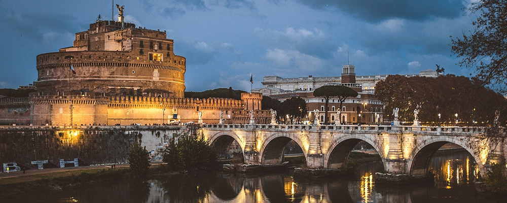 Rome airport transfers: Castel Sant'Angelo and bridge over the Tiber River at dusk.